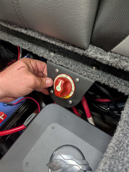 Battery switch and mounting bracket positioned at the edge of a boat battery compartment