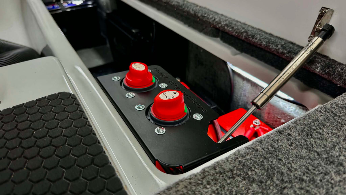 Rocket City Outdoors dual battery switch mounting bracket with two red disconnect switches installed in a boat battery compartment