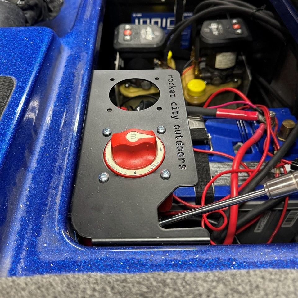 Phoenix Double Battery Switch bracket, matte black metal panel with a red rotary switch and circular mounting openings