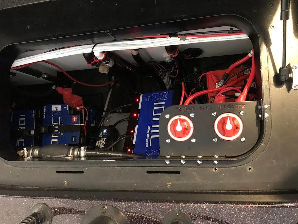Skeeter Dual Battery Switch mounting bracket with two red rotary switches on a black rectangular metal plate