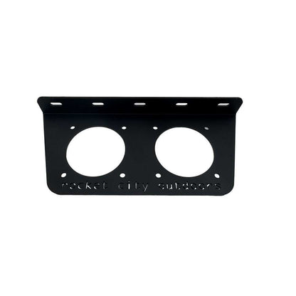Universal dual battery switch mounting bracket in matte black coated aluminum, with two circular switch cutouts and a raised mounting lip.